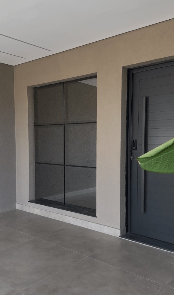Janela quadriculada e porta em alumínio preto em fachada residencial